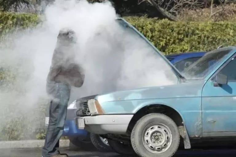 a man holding hood of overheating car